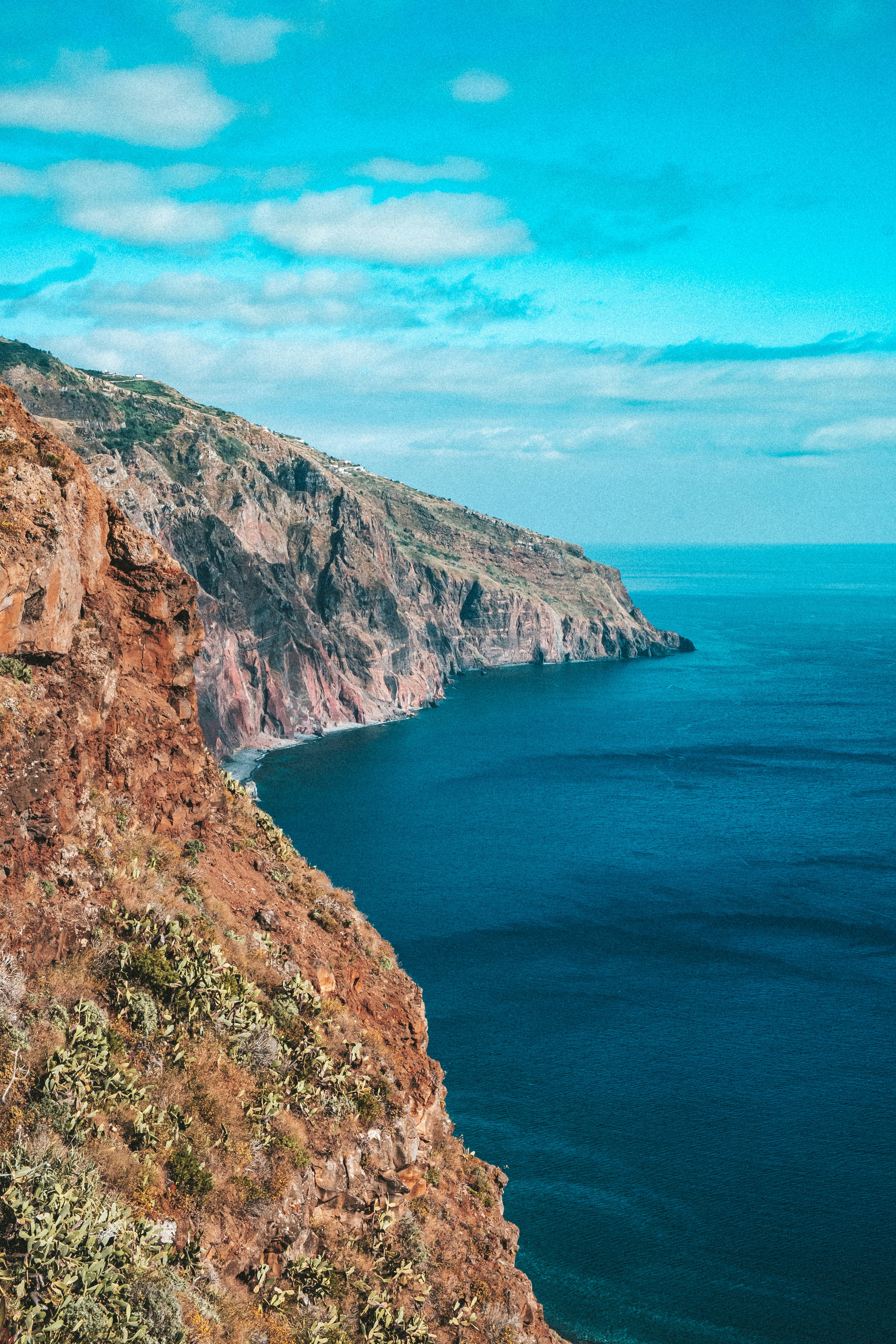 brown rocky mountain beside blue sea under blue sky during daytime